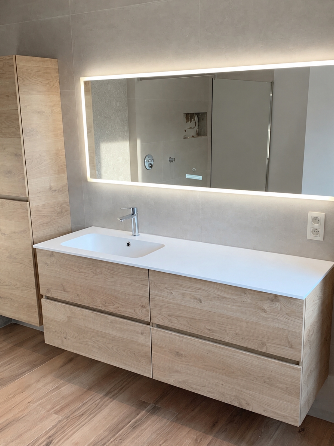 Modern houten badkamermeubel met witte wastafel en verlichte spiegel